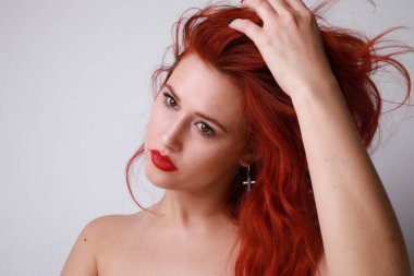 Genç kadın beyaz arka planda poz veren uzun kızıl saçlarına dokunuyor. Model-up. Yüksek kalite fotoğraf.