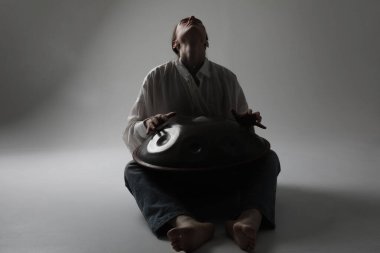 Kadın, beyaz arka planda duran davul sapıyla rahatlatıcı müzik çalıyor. Yüksek kalite fotoğraf.