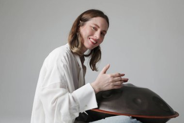 Kadın, beyaz arka planda duran davul sapıyla rahatlatıcı müzik çalıyor. Yüksek kalite fotoğraf.