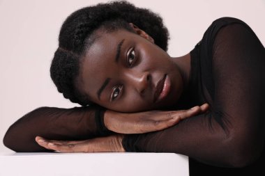 Genç Amerikalı kadın portresi kameraya özgüvenle bakıyor. Basit bir ifade var. Düşünce ve düşünce derinliğini beyaz arkaplan üzerinde gösteriyor..