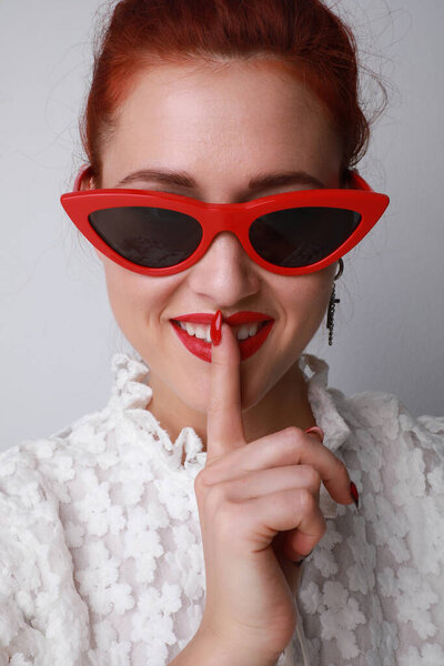 Portrait of young woman wearing cat-eye sunglasses posing on white background. High quality photo.