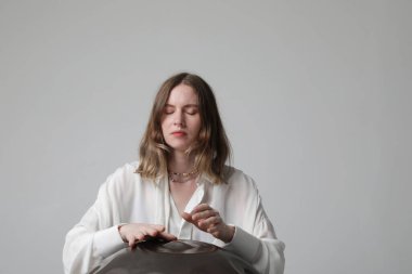 Kadın, beyaz arka planda duran davul sapıyla rahatlatıcı müzik çalıyor. Yüksek kalite fotoğraf.