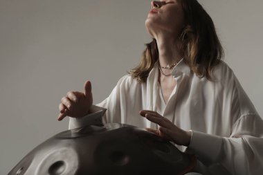 Kadın, beyaz arka planda duran davul sapıyla rahatlatıcı müzik çalıyor. Yüksek kalite fotoğraf.