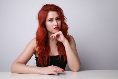 Beyaz arka planda poz veren uzun kızıl saçlı çarpıcı bir genç kadın. Model-up. Yüksek kalite fotoğraf.
