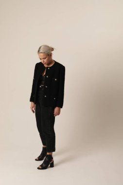 Beyaz arka planda siyah ceket giyen genç bir kadının dikey portresi. Yüksek kalite fotoğraf.