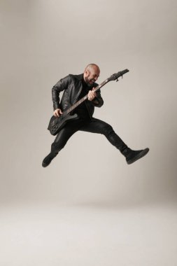 Rock müzisyeni. Elektro gitarlı bir adam stüdyoya atlıyor. Dikey. Yüksek kalite fotoğraf.