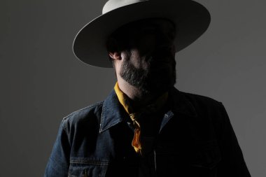 Şapkalı ve kot ceketli bir adamın içeri bakıp poz verdiği bir fotoğraf. Yüksek kalite fotoğraf.