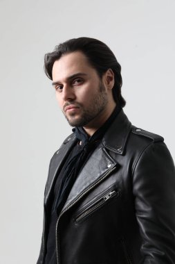 Motosiklet ceketi giyen şık sakallı genç adam kameraya bakıyor. Dikey. Yüksek kalite fotoğraf.