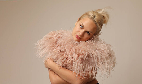 Beauty portrait of beautiful blond young woman wearing pink marabou feathers. High quality photo.
