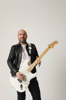 Rock müzisyeninin dikey portresi gitar çalar ve beyaz arka planda poz verir. Yüksek kalite fotoğraf.