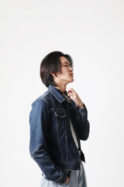 Kot ceketli yakışıklı Asyalı adamın içeride poz verdiği bir fotoğraf. Dikey. Yüksek kalite fotoğraf.