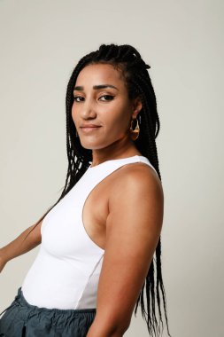 Uzun siyah örgülü, kameraya bakan Afro-Amerikan genç bir kadının dikey portresi. Yüksek kalite fotoğraf.