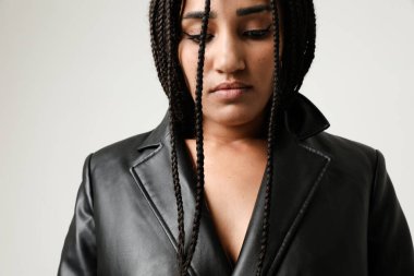 Beyaz arka planda poz veren uzun siyah ceket giyen kendine güvenen Afro-Amerikan kadın. Yüksek kalite fotoğraf.