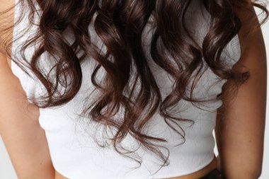 Lüks kıvırcık uzun saçlı bir kadının kesilmiş portresi. Dikey. Yüksek kalite fotoğraf.