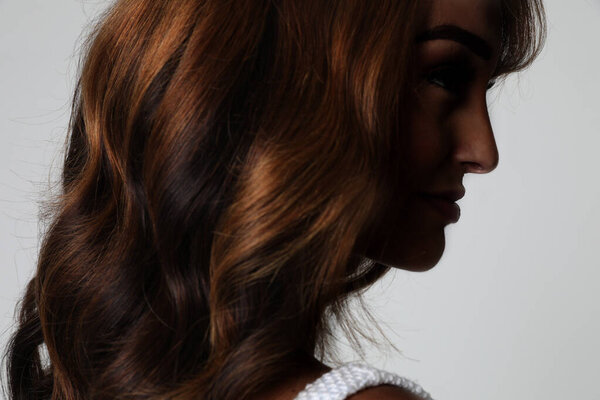 Портрет красивой молодой женщины с роскошными вьющимися длинными волосами. Вид сзади. Высокое качество фото.