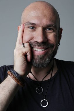 Sakallı, olgun ve kel bir adamın portresi. İçeride rahatça poz veriyor. Dikey. Yüksek kalite fotoğraf.