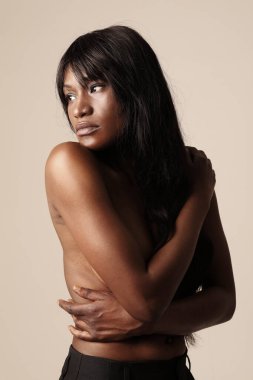 Beyaz duvarın üzerinde poz veren uzun saçlı, koyu tenli güzel bir kadının yakın çekimi. - Evet. Yüksek kalite fotoğraf.