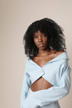 Siyah tenli, siyah saçlı, içeride poz veren genç bir kadın. Zihinsel ve zihinsel sağIık. Dikey. Yüksek kalite fotoğraf.