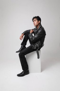 Motosiklet ceketi giyen ve beyaz arka planda poz veren yakışıklı bir adamın portresi. Dikey. Yüksek kalite fotoğraf