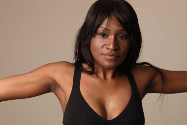 Beyaz duvarın üzerinde poz veren uzun saçlı, koyu tenli güzel bir kadının yakın çekimi. - Evet. Yüksek kalite fotoğraf.