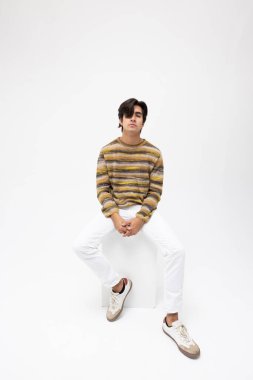 Beyaz arka planda poz veren yakışıklı genç adamın dikey portresi. Zihinsel ve zihinsel sağlık. Yüksek kalite fotoğraf.