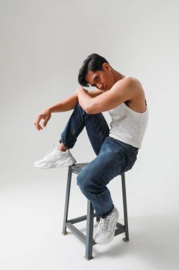 Beyaz arka planda dikey poz veren düşünceli Asyalı bir adamın portresi. Yüksek kalite fotoğraf.