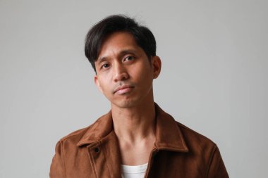 Beyaz arka planda poz verip kameraya bakan Asyalı adamın portresi. Yüksek kalite fotoğraf