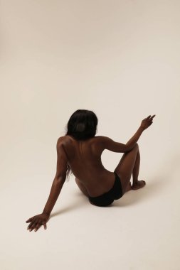 Beyaz duvarın üzerinde poz veren esmer tenli genç bir manken. Dikey. Yüksek kalite fotoğraf.