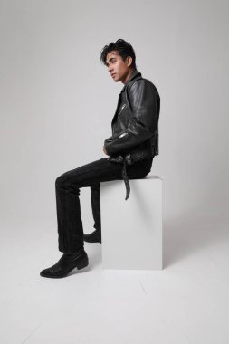 Motosiklet ceketi giyen ve beyaz arka planda poz veren yakışıklı bir adamın portresi. Dikey. Yüksek kalite fotoğraf