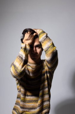 Siyah saçlı beyaz arka planda poz veren genç bir adamın yan portresi. Dikey. Yüksek kalite fotoğraf.