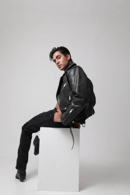 Motosiklet ceketi giyen ve beyaz arka planda poz veren yakışıklı bir adamın portresi. Dikey. Yüksek kalite fotoğraf