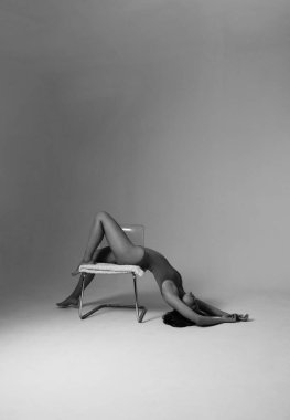 Stüdyoda egzersiz yapan, yoga yapan, esnek bir vücut giysisi giyen güzel, hoş bir kadın. Yaşam tarzı. Yüksek kaliteli siyah beyaz fotoğraf.