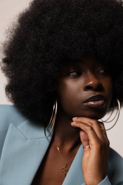 Mavi takım elbise giyen afro saçlı neşeli bir kadının stüdyo portresi. Dikey. Yüksek kalite fotoğraf.