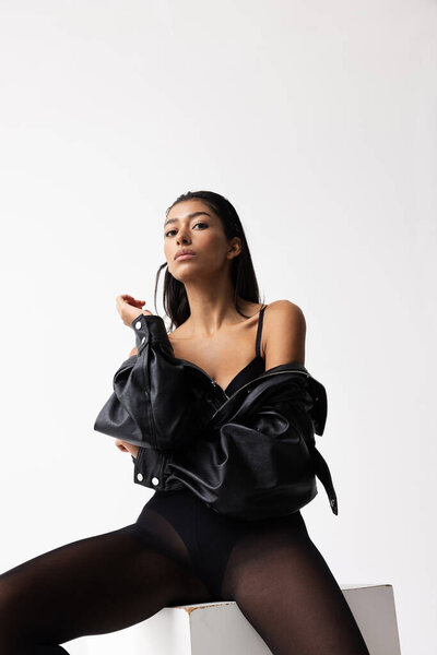 Портрет красивой молодой индийской женщины носит черную кожаную куртку. По вертикали. Высокое качество фото.