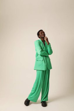 Genç Afrikalı Amerikalı adam yeşil takım elbise giyiyor ve arka planda poz veriyor. Dikey maket. Yüksek kalite fotoğraf.