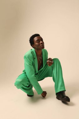 Yeşil takım elbiseli genç Afro-Amerikalı adam arka planda poz veriyor. Dikey maket. Yüksek kalite fotoğraf.
