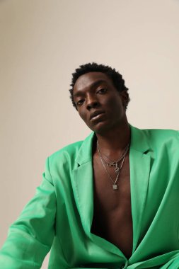 Yeşil takım elbiseli genç Afro-Amerikalı adam arka planda poz veriyor. Dikey maket. Yüksek kalite fotoğraf.