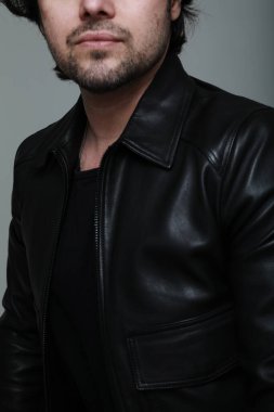 Siyah ceket giyen ve kameraya bakan sakallı yakışıklı bir adam portresi. Dikey. Yüksek kalite fotoğraf