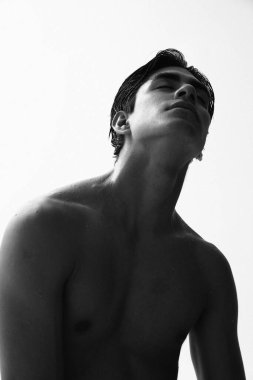 Beyaz arka planda üstsüz poz veren yakışıklı genç adamın siyah beyaz portresi. Yüksek kalite fotoğraf