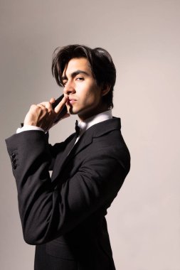 Zarif siyah takım elbiseli yakışıklı bir genç ve beyaz arka planda akıllı telefon kullanıyor. İzole edilmiş. Yüksek kalite fotoğraf.