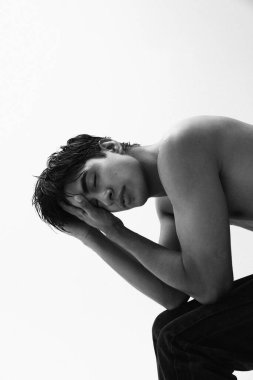 Beyaz arka planda üstsüz poz veren yakışıklı genç adamın siyah beyaz portresi. Yüksek kalite fotoğraf