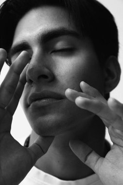 Beyaz arka planda poz veren yakışıklı genç adamın siyah beyaz portresi. Yüksek kalite fotoğraf