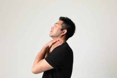 Genç Asyalı adam boynuna dokunuyor ve acı çekiyor. Dikey. Yüksek kalite fotoğraf.