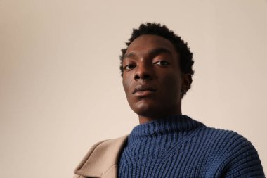 Açık arkaplanda mavi süveter giyen Afro-Amerikan bir adamın vesikalığı. Model-up. Yüksek kalite fotoğraf.