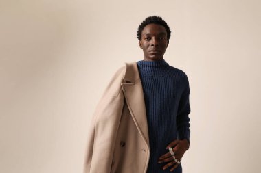 Genç Afro-Amerikan bir adamın portresi açık arkaplanda poz veren kışlık bir ceket giyiyor. Yüksek kalite fotoğraf.