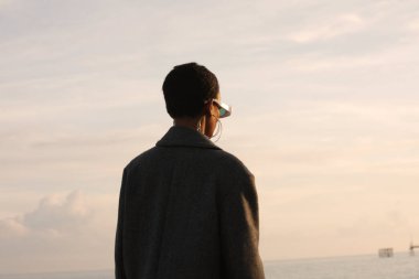 Koyu tenli, kısa saçlı, açık havada poz veren genç bir kadının arka görüntüsü. Yüksek kalite fotoğraf.