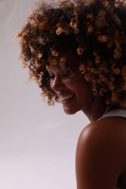 Kıvırcık saçlı, güzel ve mutlu Afro-Amerikan kadın bakışları başka yöne bakıyor. Dikey. Yüksek kalite fotoğraf.