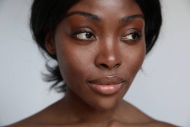 Kusursuz cildini ve güzel makyajını sergileyen doğal güzelliği olan Afro-Amerikan bir kadının çarpıcı portresi. Yüksek kalite fotoğraf.