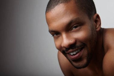 Gri arka planda poz veren sakallı genç bir zenci. Mesajın için yer aç. Yüksek kalite fotoğraf.