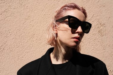 Pembe saçlı, güneş gözlüğü takan genç bir kadının fotoğrafı. Yüksek kalite fotoğraf.